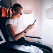 Woman on an airplane using Wifi on her phone
